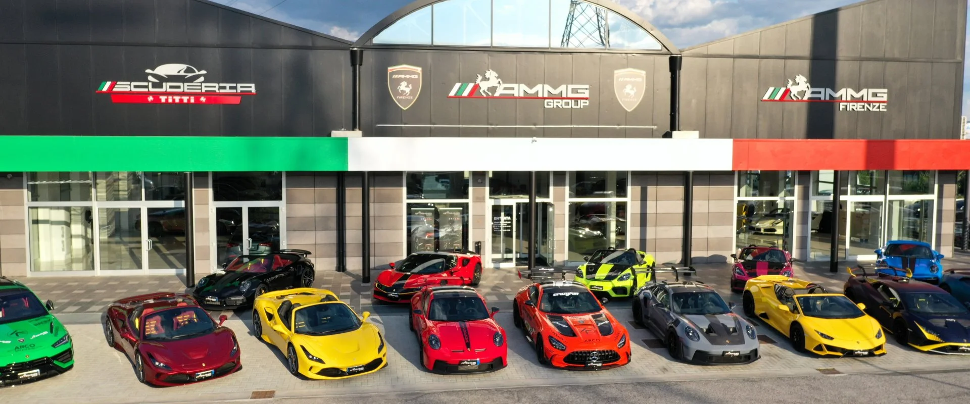 The AMMG Group showroom in Calenzano near Florence, a row of Ferrari, Lamborghini and McLaren supercars parked in front of the building