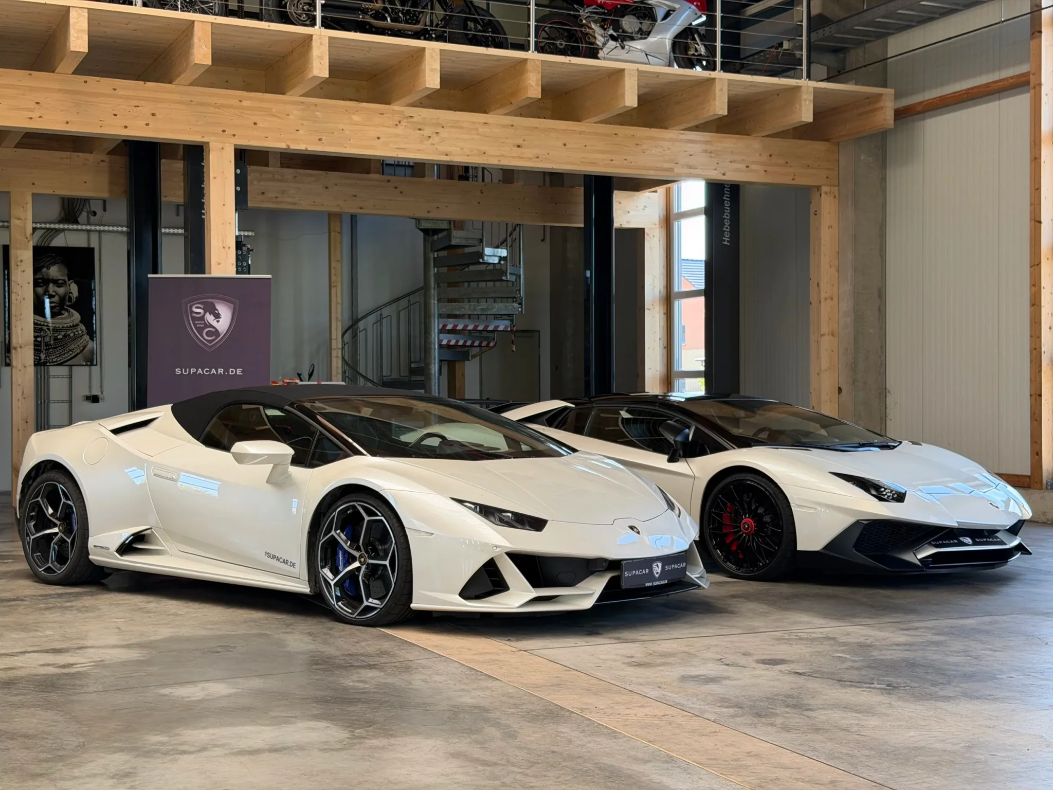 Zwei weiße Lamborghini, vorn ein Huracán EVO Spyder, im SUPACAR-Showroom der EM Handelsagentur in Kranzberg