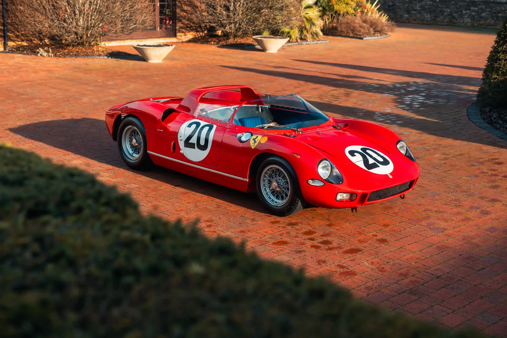 Ferrari 275 P rouge au numéro 20, vue de trois-quarts avant dans la cour pavée de briques de Belchers Farm