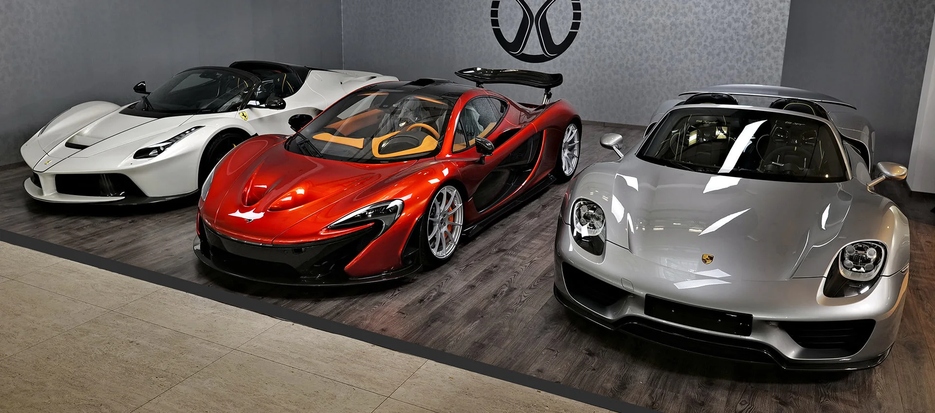 A white Ferrari LaFerrari Aperta, an orange McLaren P1 and a silver Porsche 918 Spyder side by side in the Mansory Automotive CZ showroom in Prague