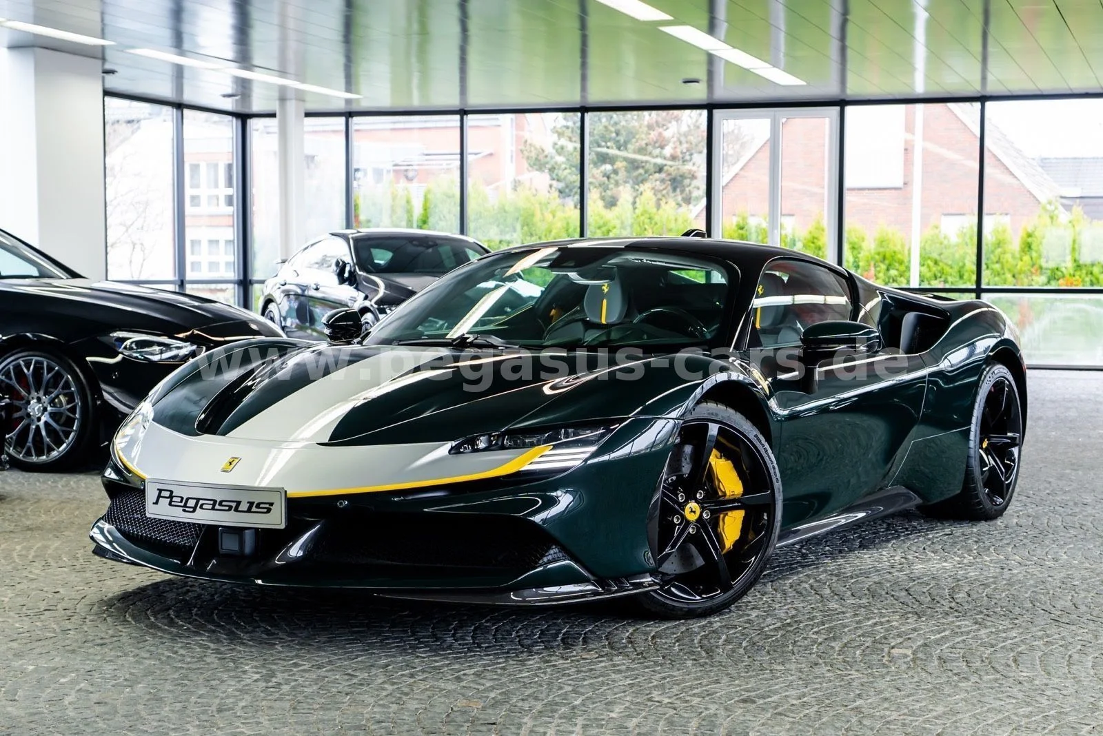 Ein dunkelgrüner Ferrari SF90 Stradale mit silbern-gelber Lackierung im Showroom von Pegasus exclusive cars in Mönchengladbach, dahinter weitere Fahrzeuge vor der Glasfront
