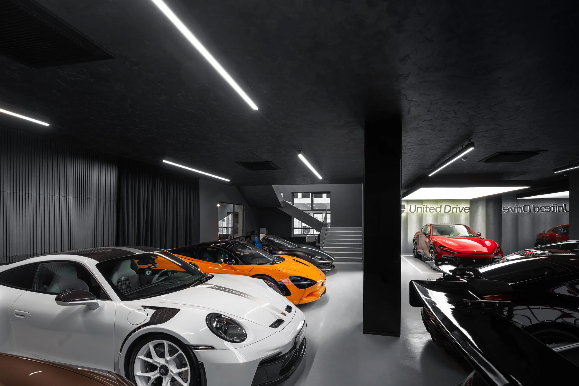 Der Showroom von United Drive in Voluntari, vorn ein weißer Porsche 911 GT3 RS und ein orangefarbener McLaren